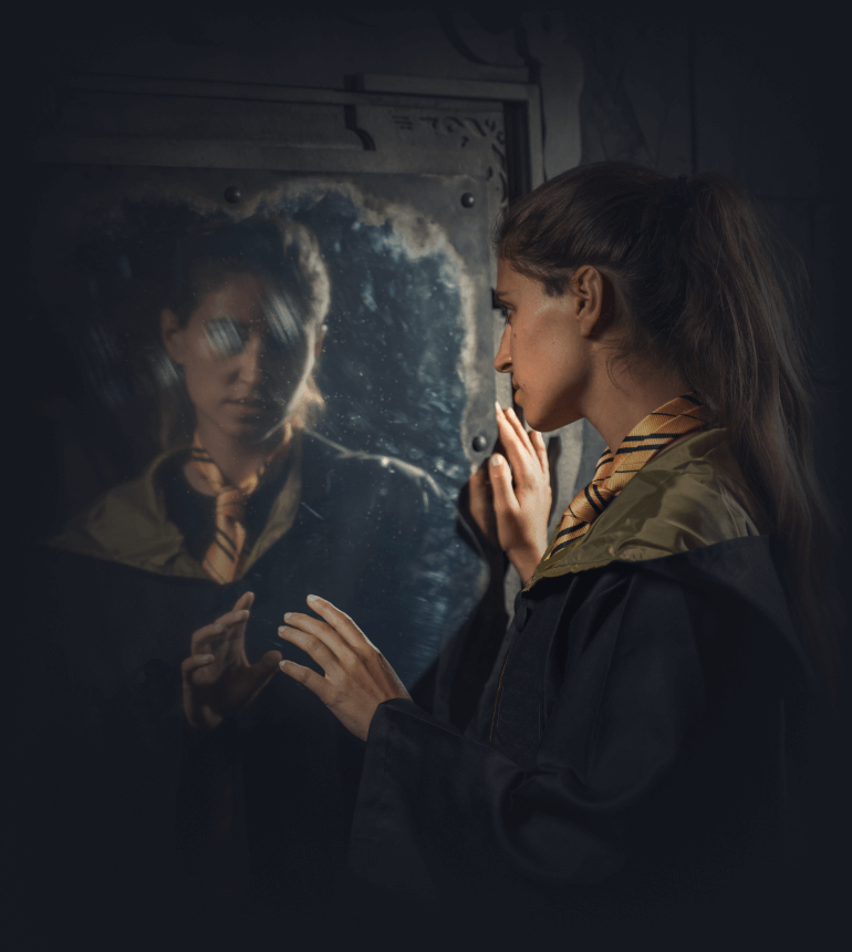 Une jeune magicienne observant un miroir mystérieux dans l'escape game sur le thème de la magie et de la sorcellerie à Lyon